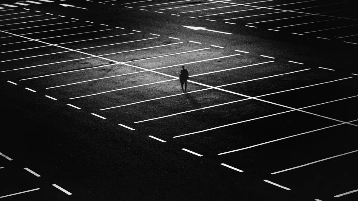 Mężczyzna czytający książkę na tle miejskiego parkingu.