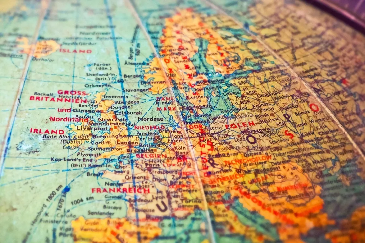 Klepsydra na biurku wśród starych map i dokumentów, symbolizująca podróż w czasie i alternatywne scenariusze historyczne.
